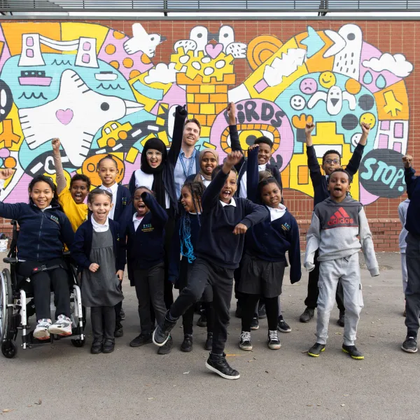 Group of primary school children in front of a colourful seagull themed mural.