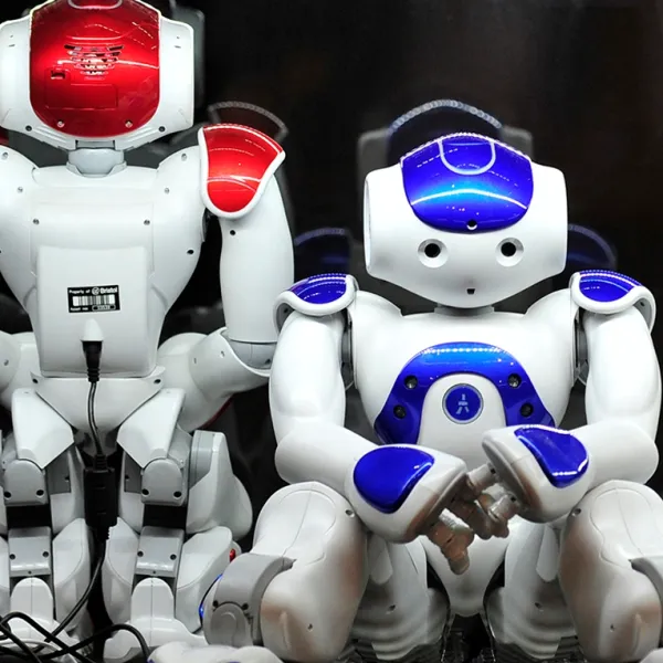 Two Noa robots - small white humanoid form with read and blue colouring