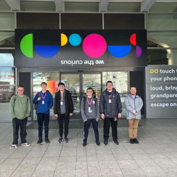 A group of six young people stood outside the front doors of We The Curious