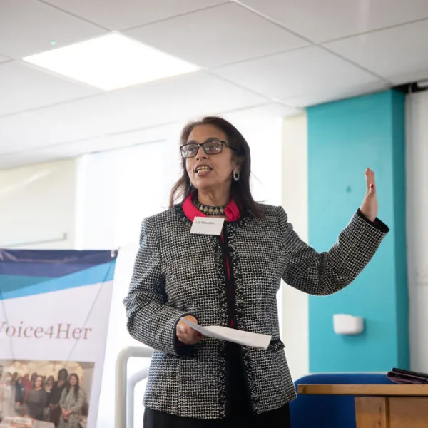 A person in a black and white blazer making a speech